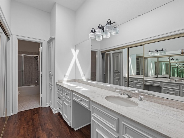 full bath with toilet, wood finished floors, bath / shower combo with glass door, and vanity