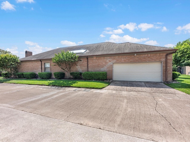 single story home featuring a garage, a chimney, driveway, and brick siding