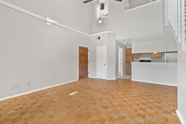 unfurnished living room with visible vents, a ceiling fan, a high ceiling, and baseboards
