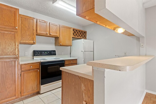 kitchen featuring electric stove, freestanding refrigerator, a textured ceiling, light countertops, and a peninsula