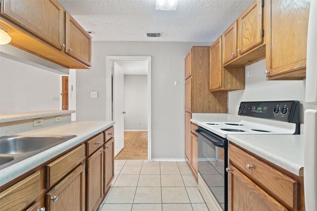 kitchen with range with electric stovetop, visible vents, light tile patterned floors, and light countertops