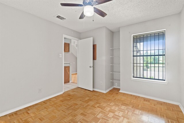 unfurnished bedroom with a textured ceiling, visible vents, a ceiling fan, and baseboards