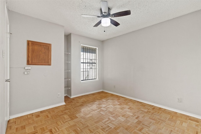 spare room featuring a textured ceiling, ceiling fan, and baseboards