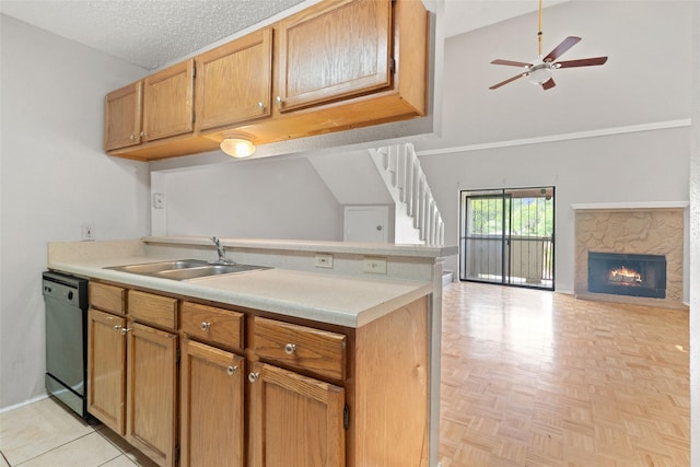 kitchen featuring black dishwasher, light countertops, a fireplace, a sink, and a towering ceiling