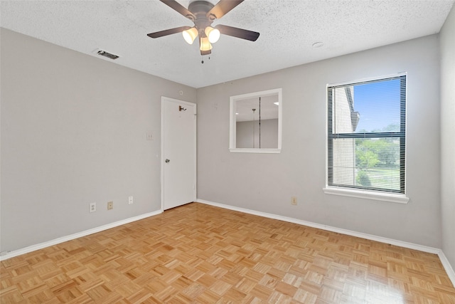 unfurnished room featuring a textured ceiling, ceiling fan, visible vents, and baseboards