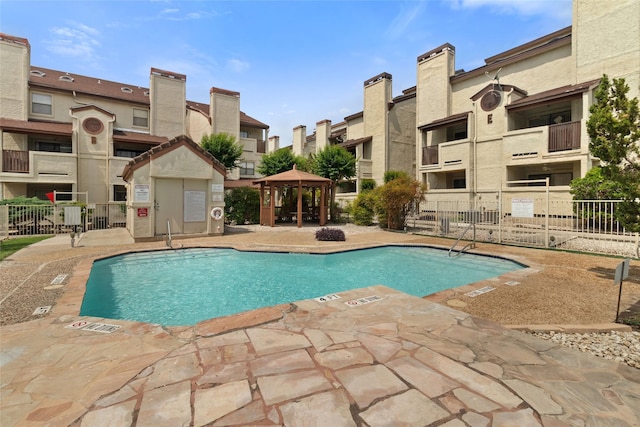 community pool with a residential view, a gazebo, a patio area, and fence