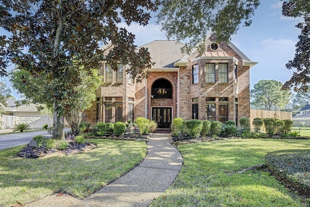 view of front of house with fence, a front lawn, french doors, and brick siding