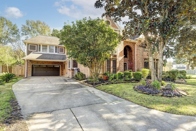 view of front facade with brick siding, fence, driveway, a front lawn, and an attached garage