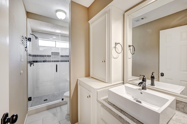 bathroom with vanity, toilet, a stall shower, visible vents, and tile patterned flooring