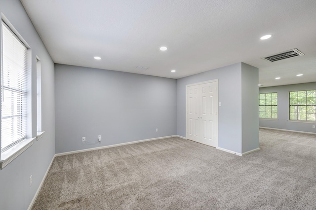 carpeted empty room featuring baseboards, recessed lighting, and visible vents