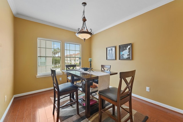 dining space with wood-type flooring, baseboards, and crown molding