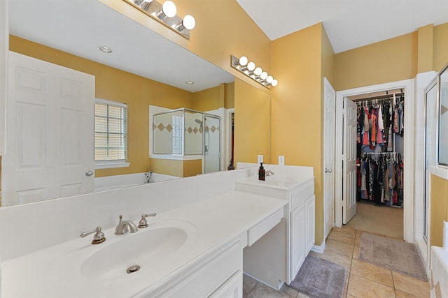 bathroom with a walk in closet, tile patterned flooring, vanity, baseboards, and a shower stall