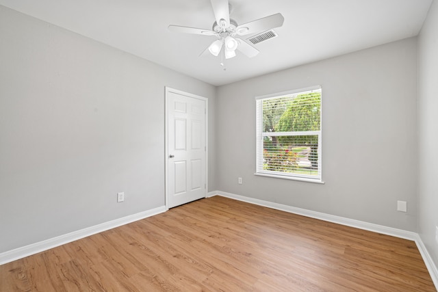 empty room featuring visible vents, ceiling fan, light wood finished floors, and baseboards
