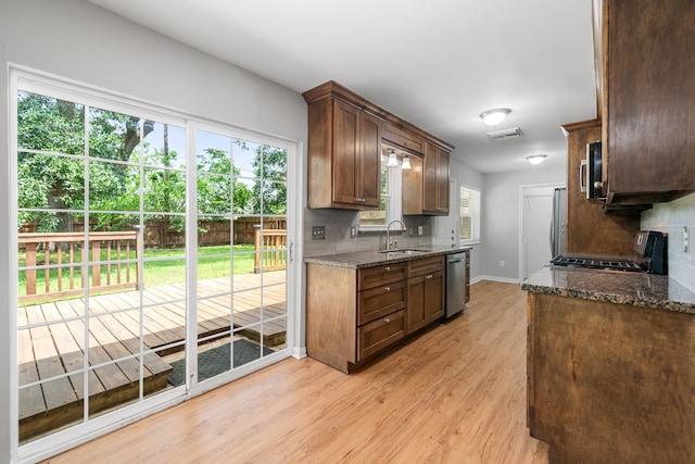 kitchen with a sink, light wood-style floors, stainless steel appliances, and tasteful backsplash