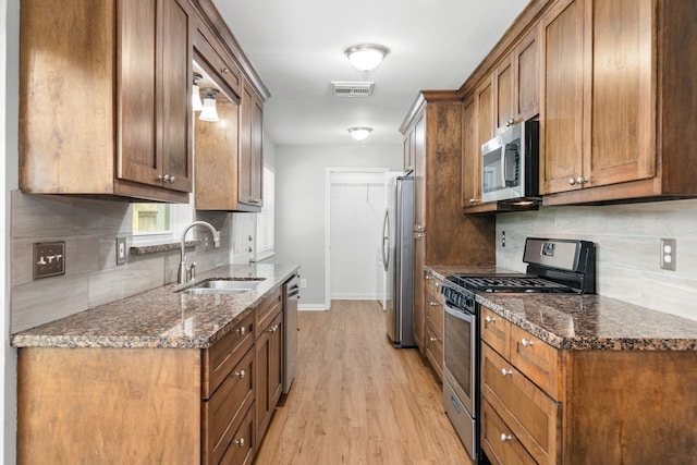 kitchen featuring a sink, appliances with stainless steel finishes, visible vents, baseboards, and backsplash