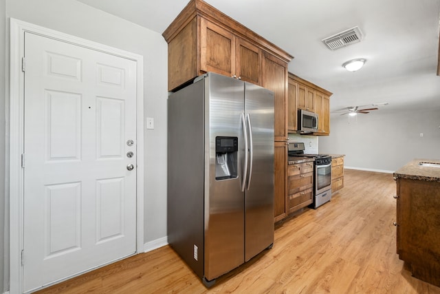 kitchen featuring visible vents, stainless steel appliances, baseboards, light wood-type flooring, and a ceiling fan
