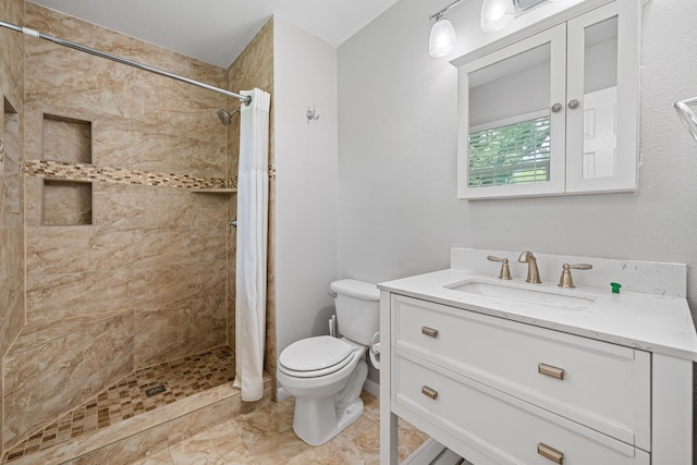 bathroom with toilet, tiled shower, and vanity