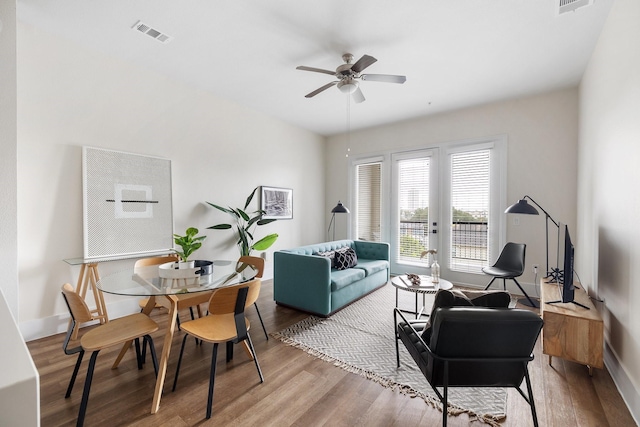 living area with wood finished floors, a ceiling fan, visible vents, and baseboards