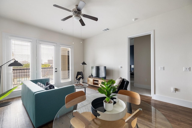 living area with baseboards, visible vents, wood finished floors, and a ceiling fan
