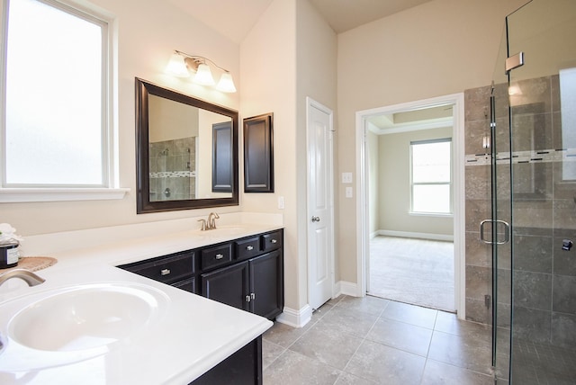 bathroom with double vanity, a stall shower, a sink, tile patterned floors, and baseboards