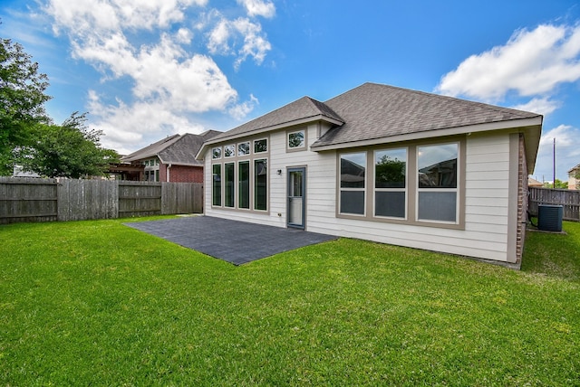 back of property with a patio, a fenced backyard, a shingled roof, a lawn, and central air condition unit