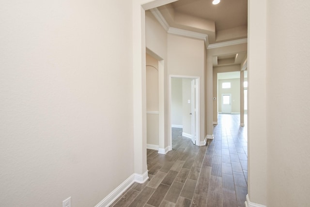 corridor featuring dark wood-type flooring, ornamental molding, baseboards, and recessed lighting