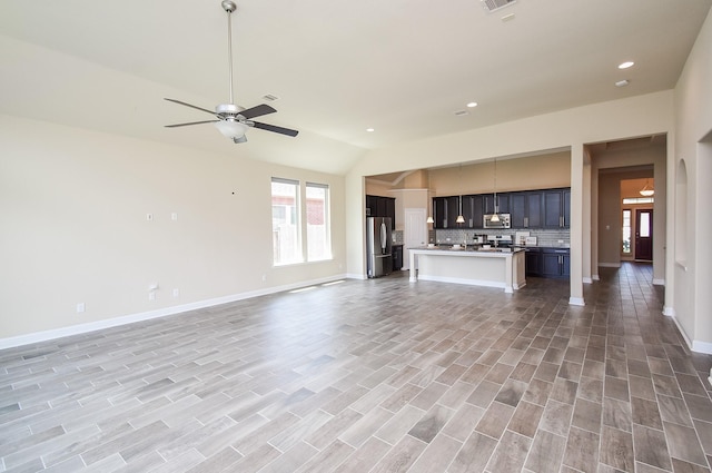 unfurnished living room with light wood-style floors, a ceiling fan, baseboards, recessed lighting, and vaulted ceiling