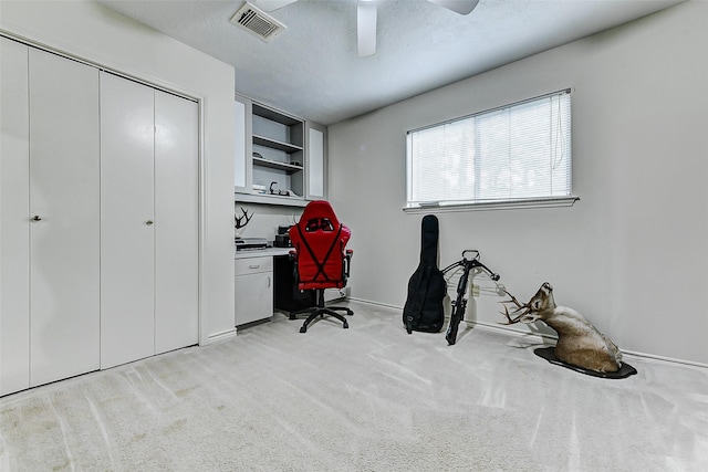 home office featuring ceiling fan, visible vents, built in study area, light carpet, and baseboards