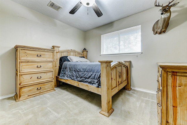 bedroom featuring baseboards, visible vents, a ceiling fan, and light colored carpet