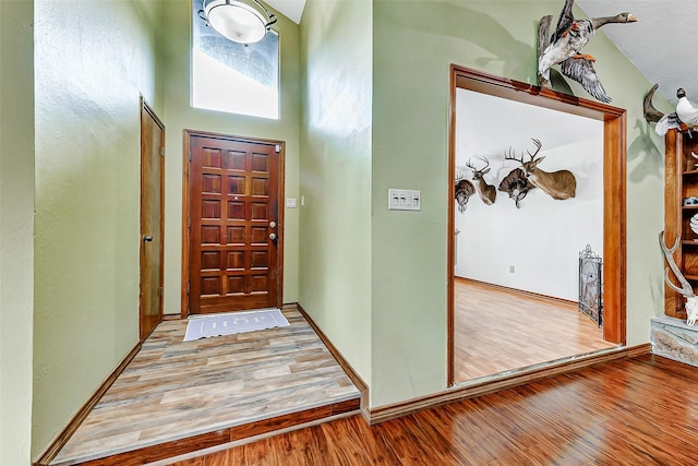 entryway with a high ceiling, wood finished floors, and baseboards