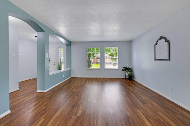3739 Apple Hollow Ln, Humble, TX 77396 - empty room with dark wood-style flooring, a textured ceiling, arched walkways, and baseboards