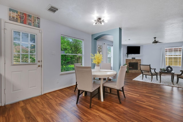3739 Apple Hollow Ln, Humble, TX 77396 - dining area with arched walkways, a fireplace with raised hearth, wood finished floors, ceiling fan, and plenty of natural light