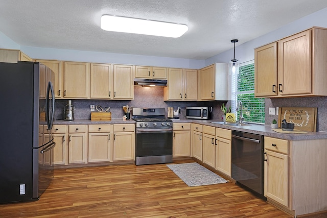 3739 Apple Hollow Ln, Humble, TX 77396 - kitchen with appliances with stainless steel finishes, light brown cabinetry, under cabinet range hood, a sink, and light wood-style floors