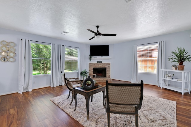 3739 Apple Hollow Ln, Humble, TX 77396 - living room featuring a textured ceiling, a fireplace with raised hearth, ceiling fan, wood finished floors, and baseboards