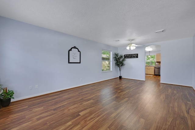 3739 Apple Hollow Ln, Humble, TX 77396 - unfurnished room with dark wood finished floors, a ceiling fan, a textured ceiling, baseboards, and arched walkways