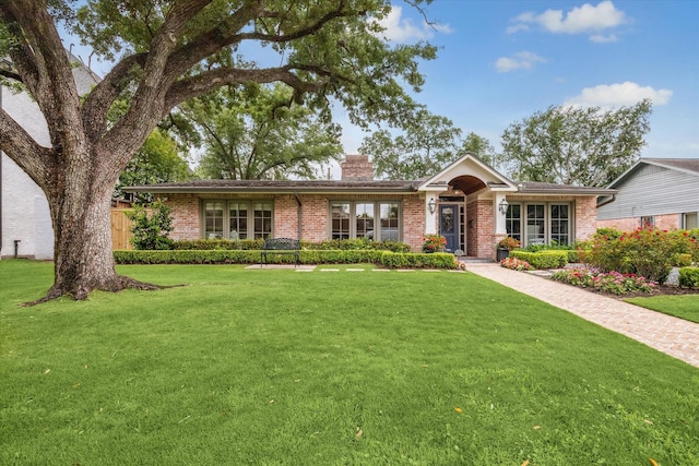single story home featuring a chimney, a front lawn, and brick siding