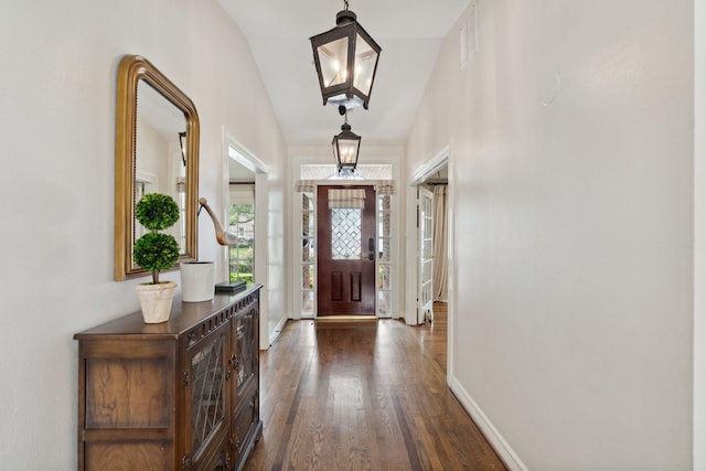foyer entrance with dark wood-type flooring, baseboards, and visible vents