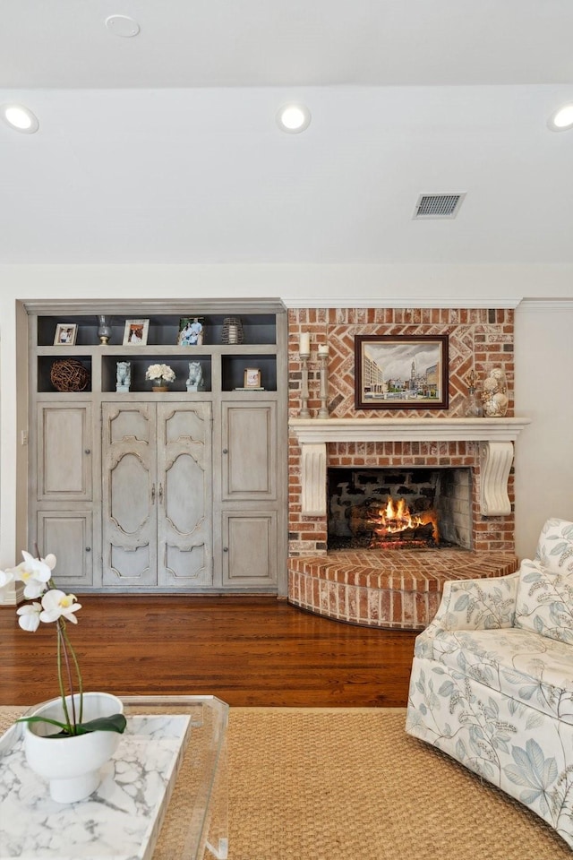 living area featuring recessed lighting, a brick fireplace, wood finished floors, and visible vents