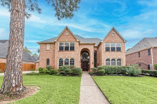 traditional-style home with brick siding, fence, and a front yard