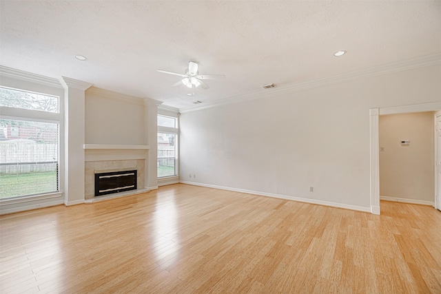 unfurnished living room with light wood-style floors, ceiling fan, baseboards, ornamental molding, and a fireplace