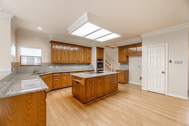 kitchen with crown molding, a sink, oven, brown cabinetry, and backsplash