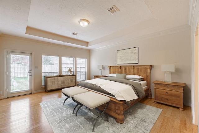 bedroom with a raised ceiling, visible vents, access to exterior, and multiple windows