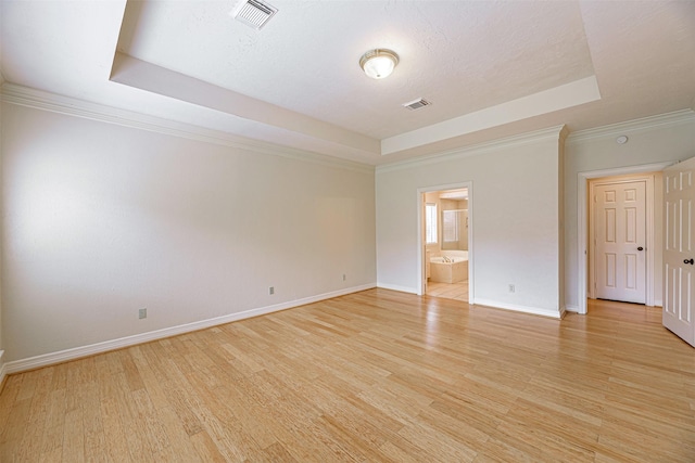 spare room featuring light wood finished floors, visible vents, and a tray ceiling