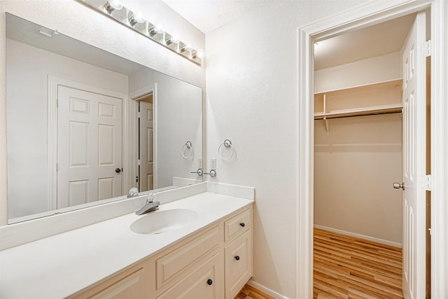 bathroom with wood finished floors, vanity, and baseboards