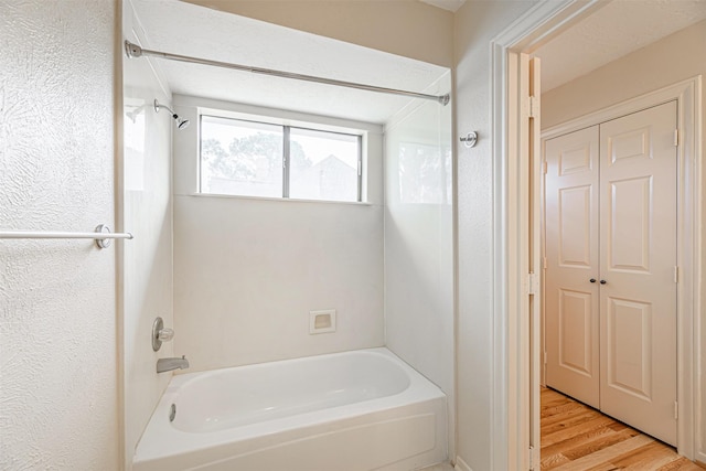 full bath featuring wood finished floors and bathtub / shower combination