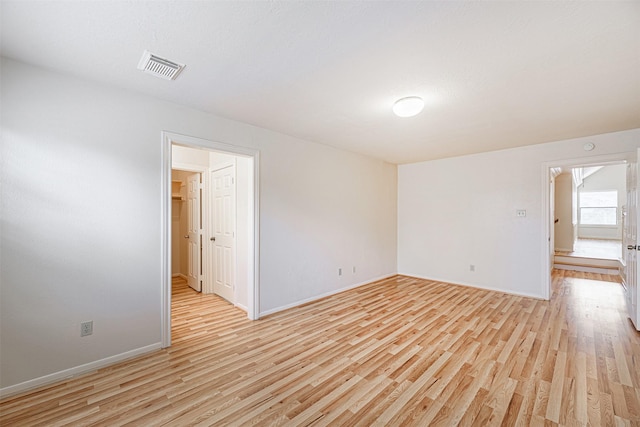 unfurnished room with baseboards, visible vents, and light wood finished floors