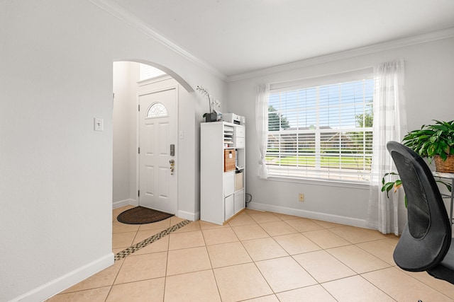 foyer featuring crown molding, arched walkways, light tile patterned floors, and baseboards