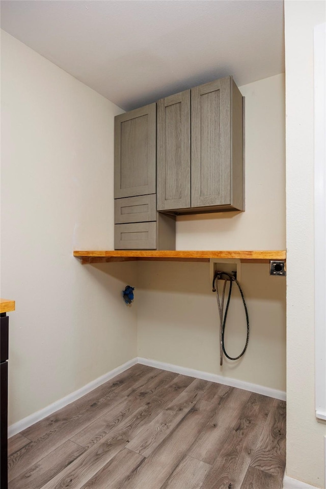 laundry room featuring hookup for a washing machine, wood finished floors, cabinet space, and baseboards
