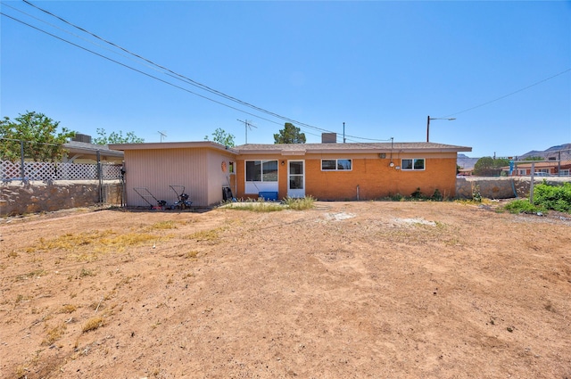 rear view of property featuring brick siding and fence