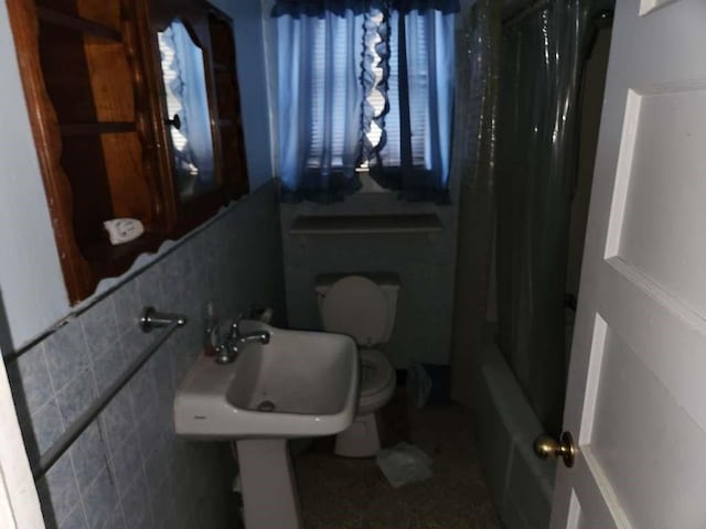 bathroom featuring toilet, shower / bath combination with curtain, and a sink